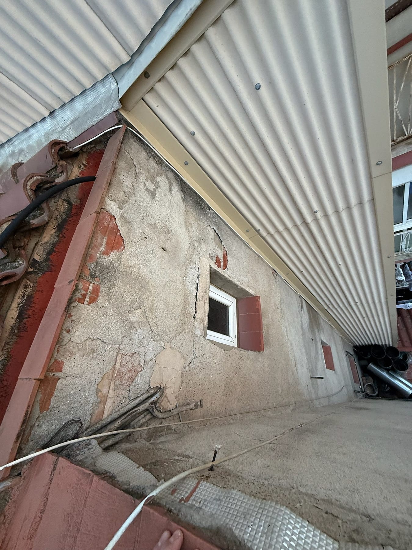 Deteriorated cladding and cracks on an interior courtyard facade
