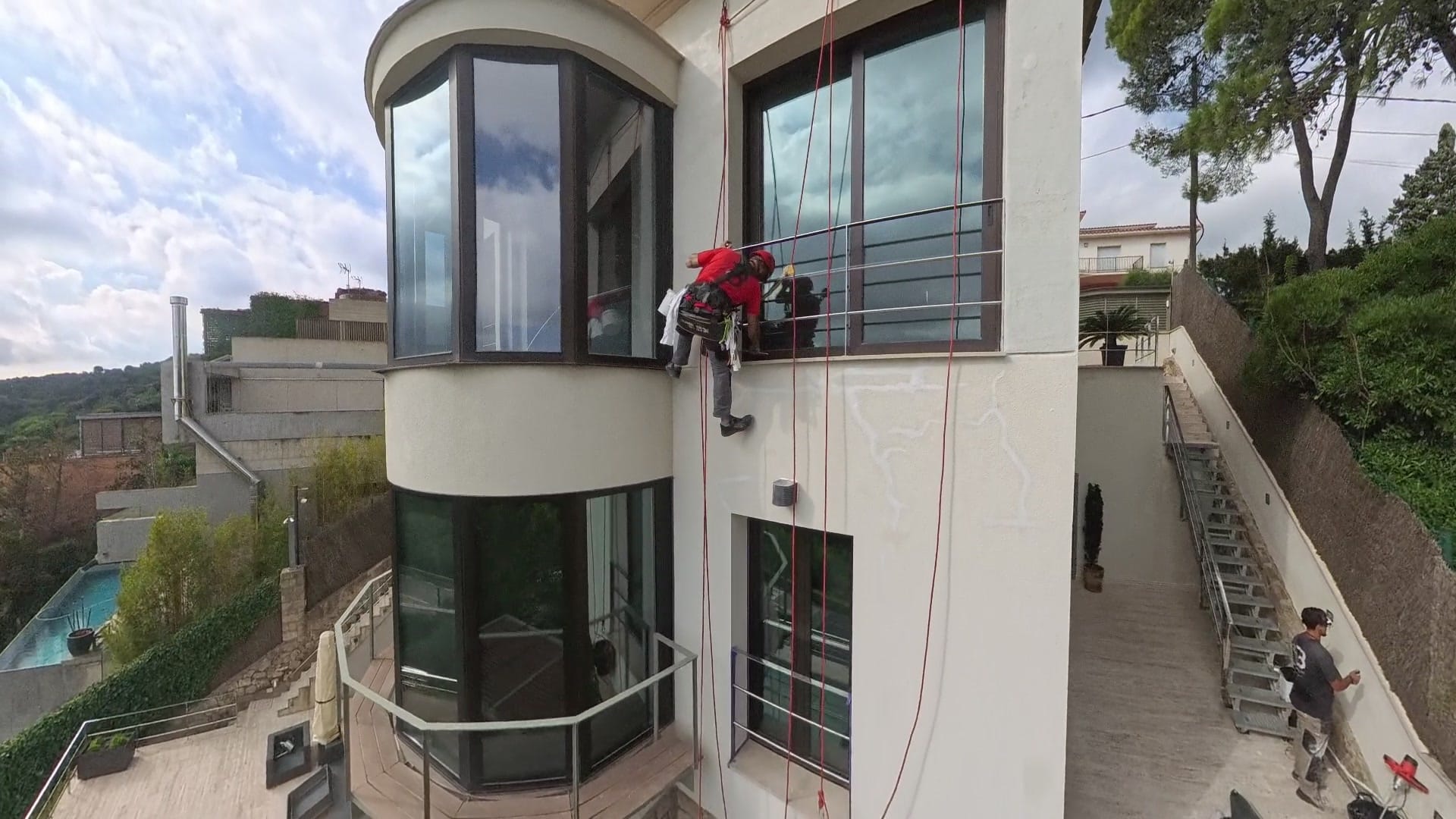 Vista de la façana d'un habitatge amb operaris suspesos mitjançant cordes