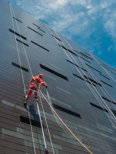 Cleaning service - A man cleaning windows on a high rise building