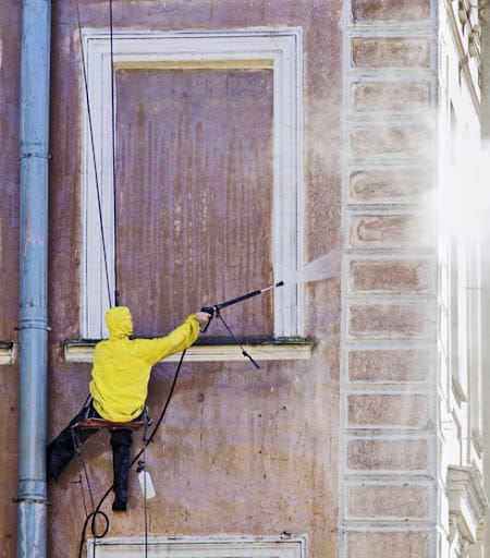 Cleaning service worker washing old building facade