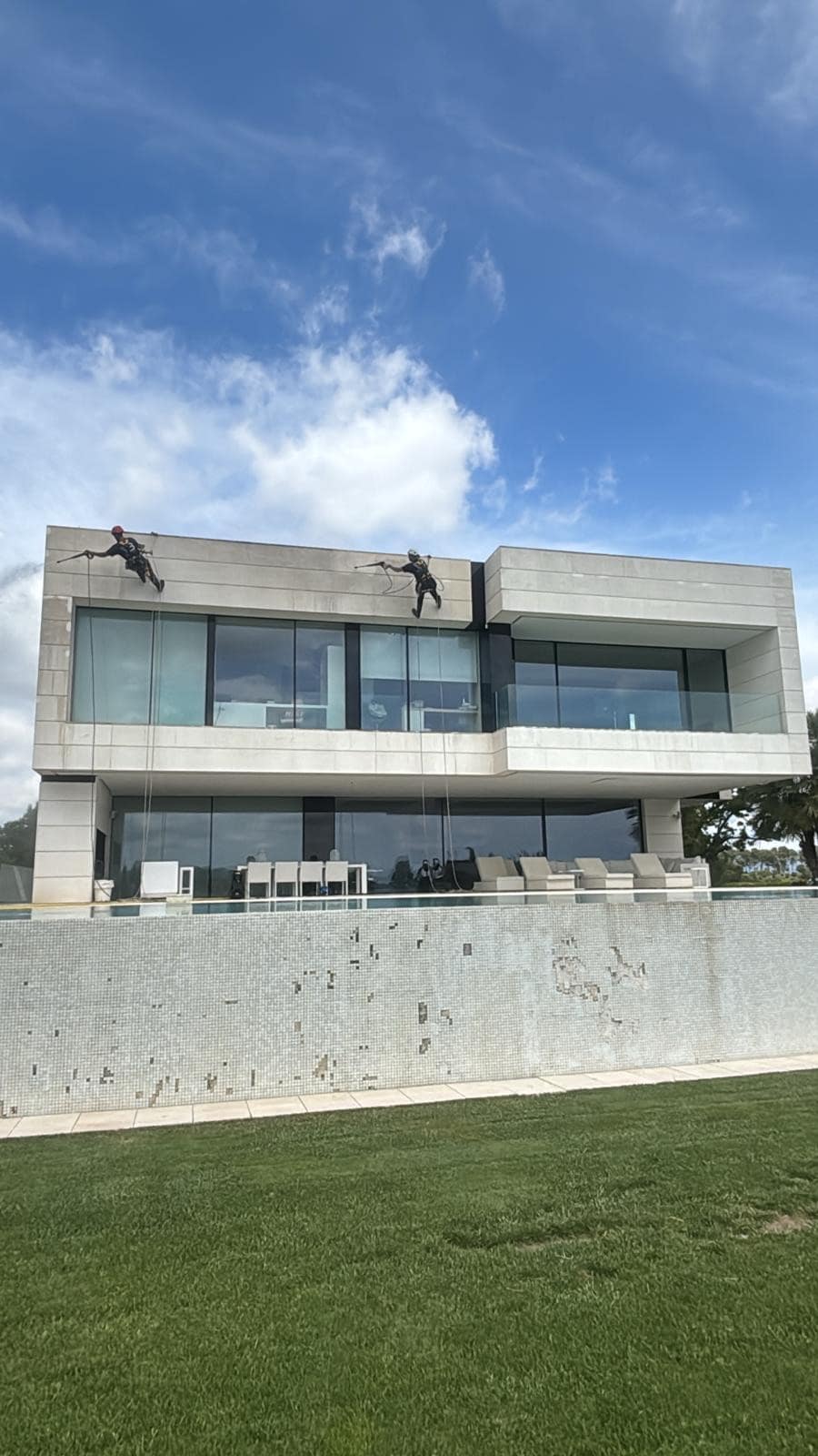 Operari realitzant treballs verticals a façana alta d'habitatge